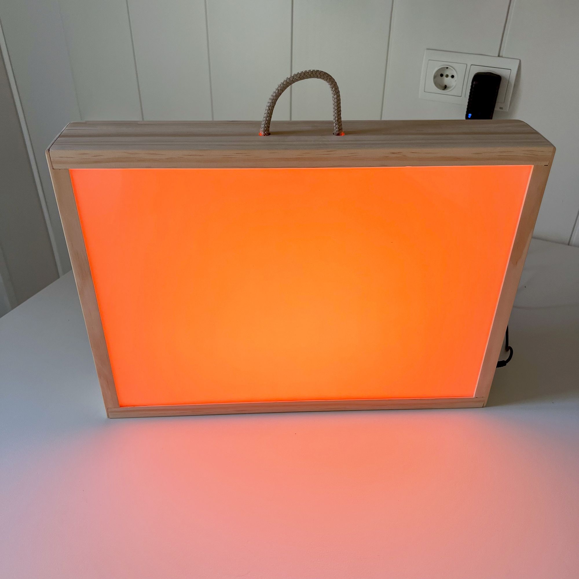 Caja de luz Montessori en funcionamiento mostrando un color naranja